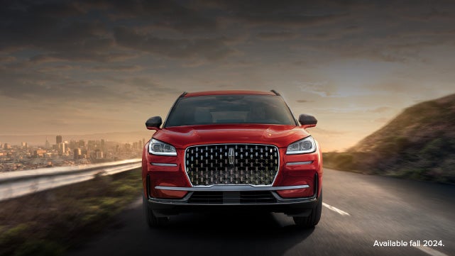 A 2025 red Lincoln Corsair® SUV is being driven down a road at sunset. | Lincoln of Ramsey in Ramsey NJ
