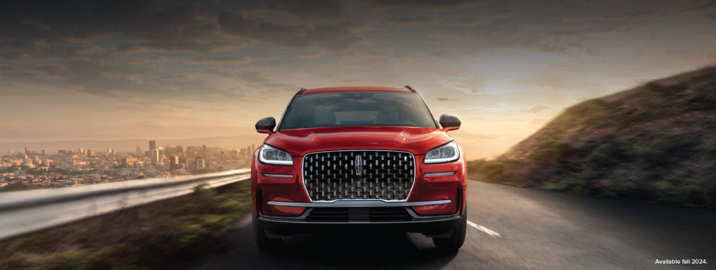 A 2025 red Lincoln Corsair® SUV is being driven down a road at sunset. | Lincoln of Ramsey in Ramsey NJ