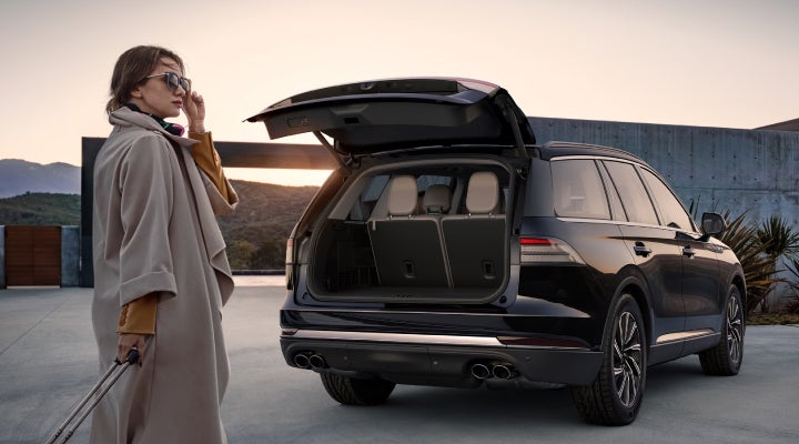 A woman approaches a 2026 Lincoln Aviator® SUV with its rear liftgate open. | Lincoln of Ramsey in Ramsey NJ