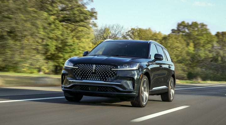 A 2026 Lincoln Black Label™ Aviator® SUV is being driven down a road lined with trees. | Lincoln of Ramsey in Ramsey NJ