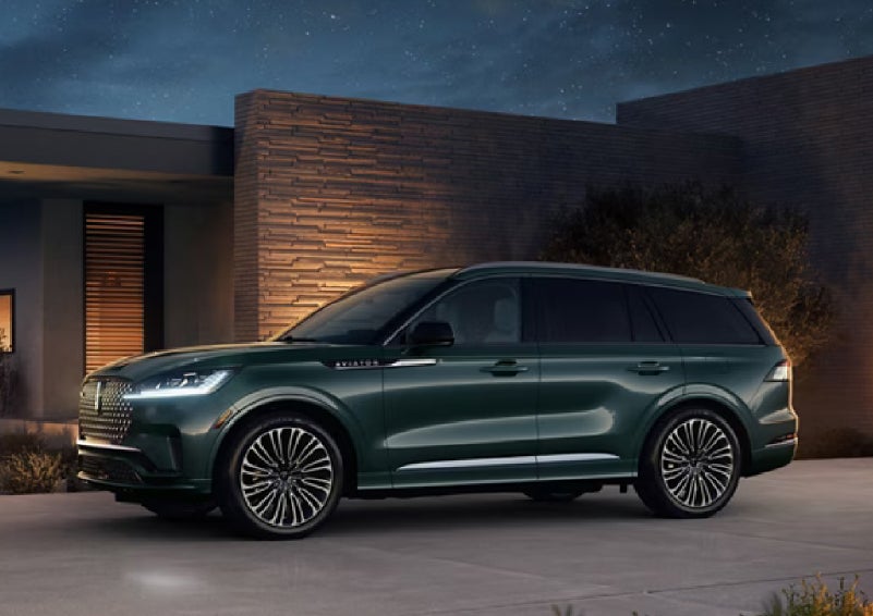 A green 2027 Lincoln Aviator® SUV is parked outside a contemporary home. | Lincoln of Ramsey in Ramsey NJ