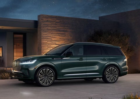A green 2027 Lincoln Aviator® SUV is parked outside a contemporary home. | Lincoln of Ramsey in Ramsey NJ