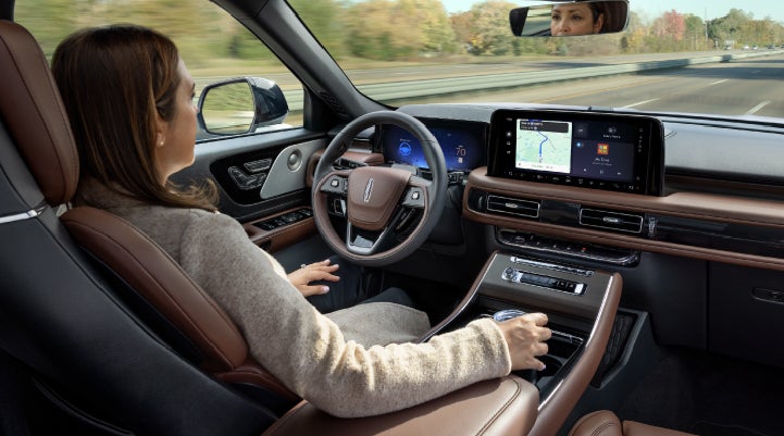 A 2027 Lincoln Aviator® SUV is being driven hands-free on a highway lined with trees. | Lincoln of Ramsey in Ramsey NJ