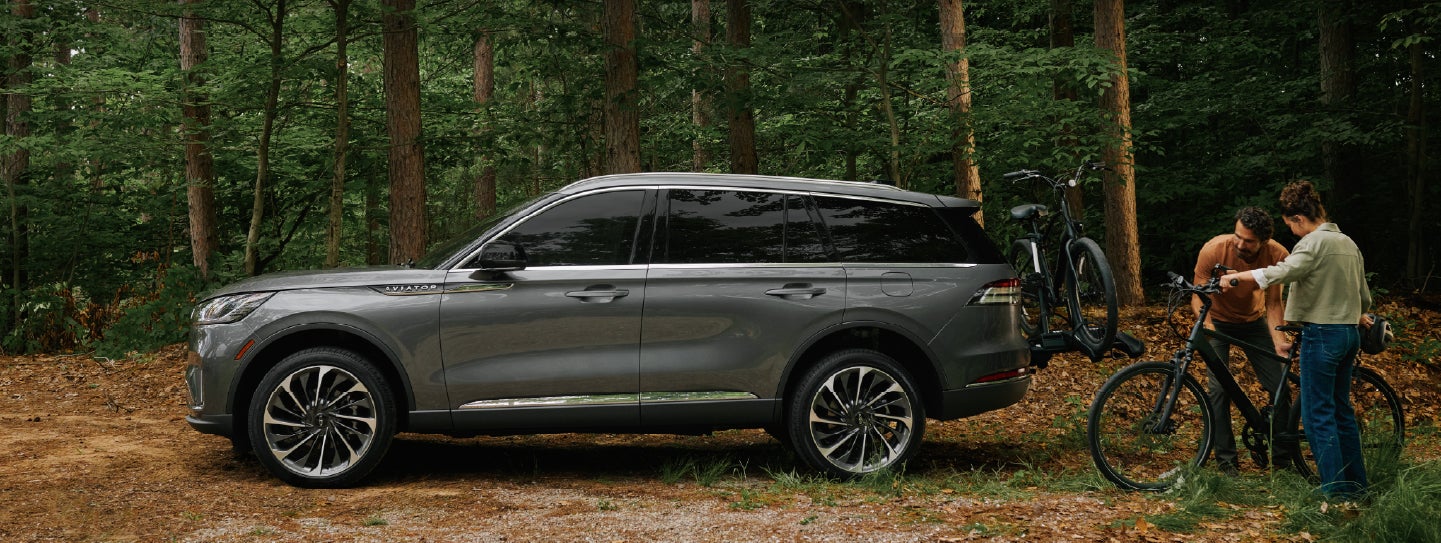 A father and son load e-bikes on a bike rack attached to a 2027 Lincoln Aviator® SUV. | Lincoln of Ramsey in Ramsey NJ
