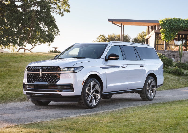A 2027 Lincoln Navigator® Black Label™ SUV is parked in the driveway of a modern home.