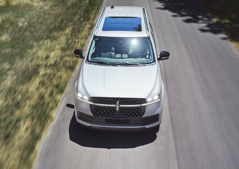 An overhead look of a 2027 Lincoln Navigator® Black Label™ SUV being driven on a country road.