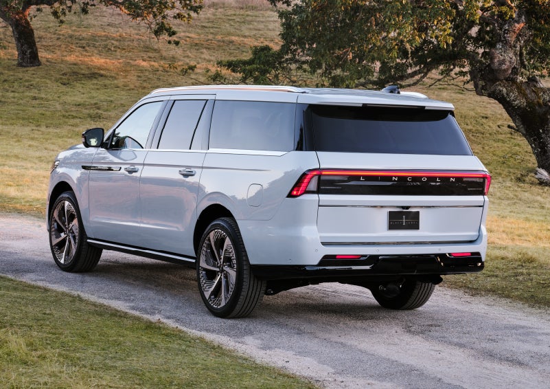 A 2027 Lincoln Navigator® Black Label™ SUV is being driven on a country road.