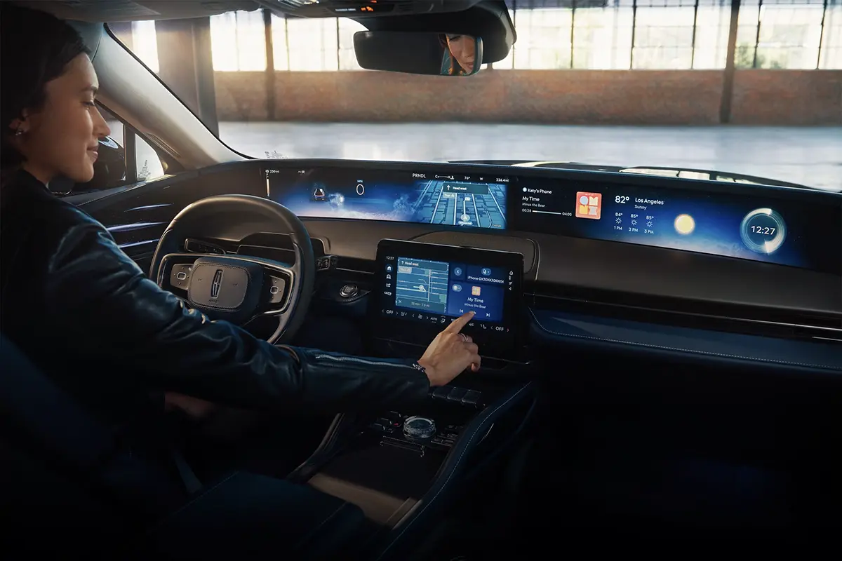 A driver interacting with the touch console of a modern vehicle interior.