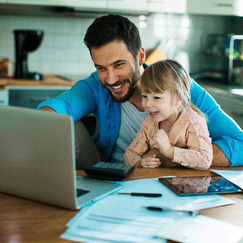 Smiling Father and young son looking at a laptop together at home
